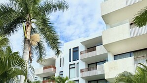 A modern building with multiple balconies, surrounded by lush greenery and a small water feature. - Vrbo Property (Nuevo Nayarit)