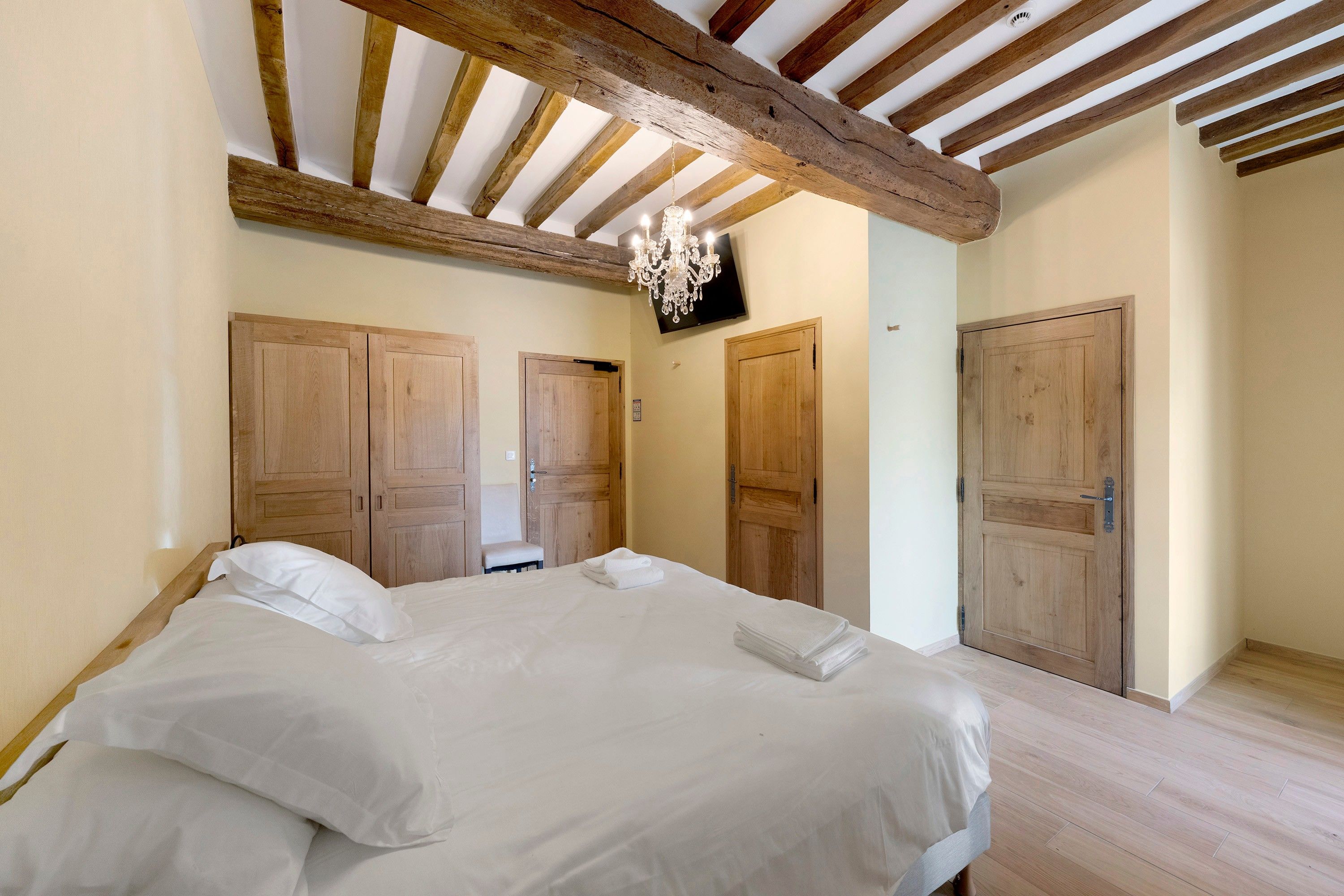 Une chambre à coucher avec un lit, une armoire en bois et un téléviseur.