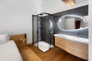 Ein modernes Badezimmer mit einer Glaskabine zur Dusche, einem Holzwaschtisch und einem großen Spiegel.