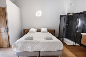 Ein Hotelzimmer mit Bett, Holztür, Duschbereich und Wandleuchte.