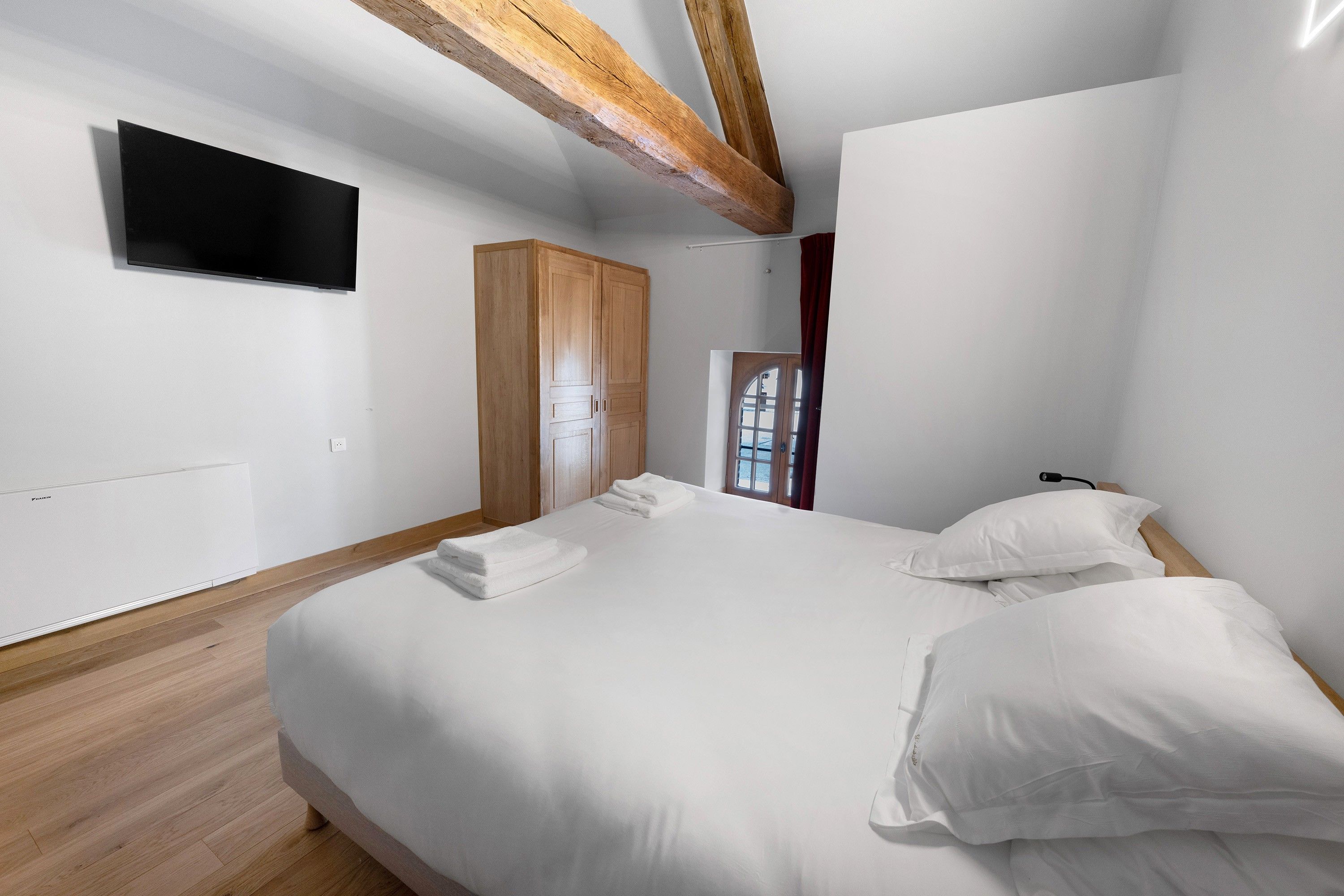 Een slaapkamer met een bed, een kledingkast, een televisie en een raam.