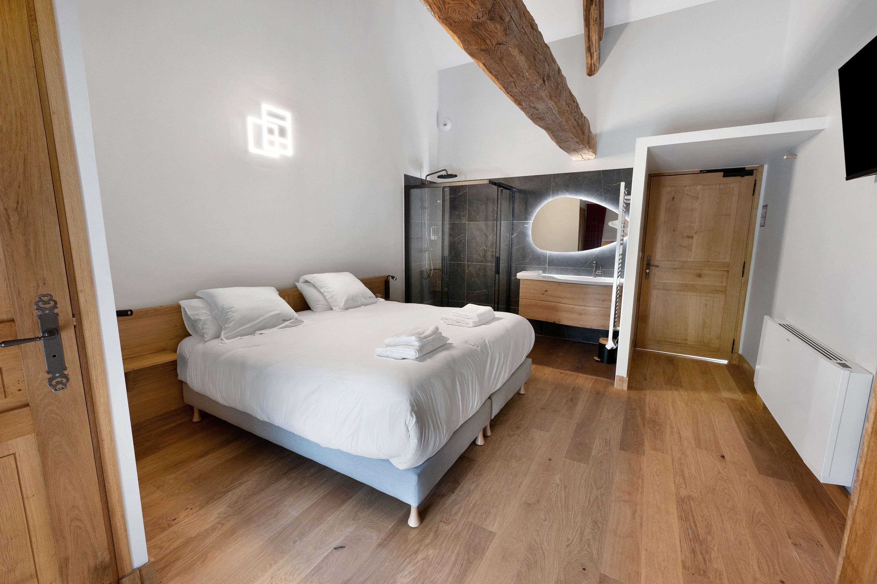 Une chambre moderne avec un grand lit, une douche intégrée et un plafond en bois.