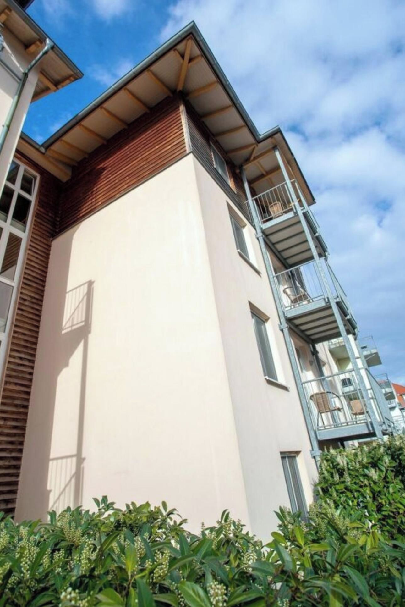 Ein mehrgeschossiges Gebäude mit einer glatten Fassade, Balkonen und blauem Himmel.