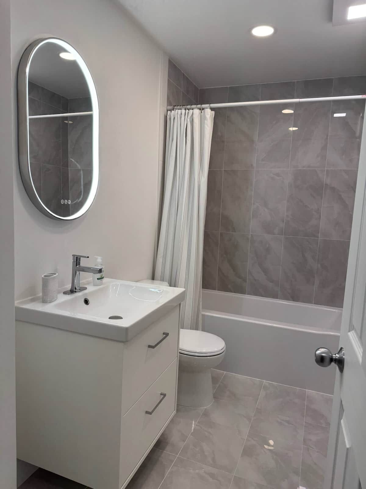 A modern bathroom with a vanity, toilet, and shower.