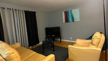 A living room with two sofas, a coffee table, a TV, and a floor lamp.