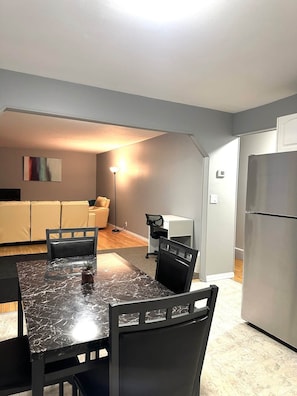 Un espacio habitable compacto con una mesa de comedor, sillas, un sofá, una lámpara de pie y un refrigerador.