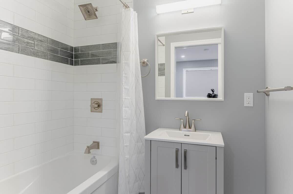 A bathroom with a bathtub, a shower, and a sink with a mirror above it.