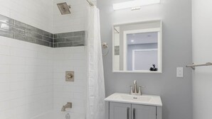 A bathroom with a bathtub, a shower, and a sink with a mirror above it. - Warm & Modern Home in Yellowknife | Sleeps 5 (Yellowknife)