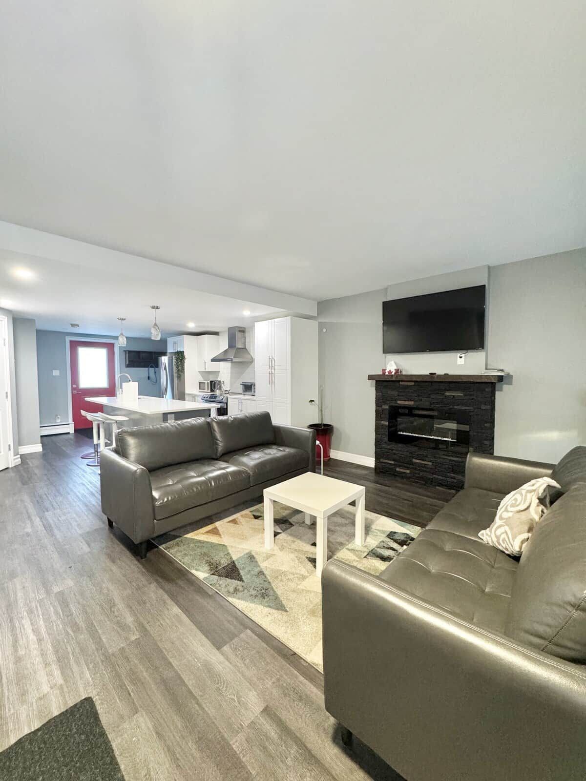A modern living room with a grey sofa, a white coffee table, and a fireplace.