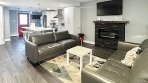 A modern living room with a grey sofa, a white coffee table, and a fireplace. - Warm & Modern Home in Yellowknife | Sleeps 5 (Yellowknife)