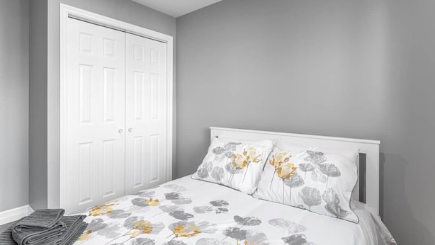 A bedroom with a bed, a wardrobe, and a folded towel on the floor. - Warm & Modern Home in Yellowknife | Sleeps 5 (Yellowknife)