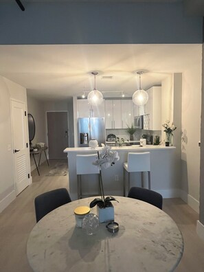 A modern kitchen with white cabinets, a central island, and pendant lighting. - Luxury 1 Bedroom Loft in Jersey City (Jersey City)