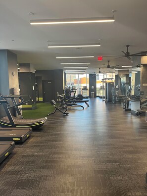 A gym with treadmills, weight machines, and a green artificial turf area. - Luxury 1 Bedroom Loft in Jersey City (Jersey City)
