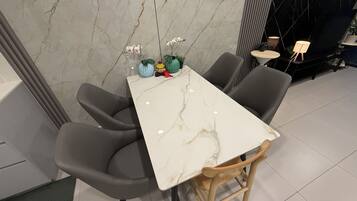 A dining area with a marble table, grey chairs, and small potted plants.