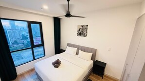 Un dormitori modern amb un llit gran, un ventilador de sostre, vista a la ciutat i una obra d'art amb zebres a la paret.