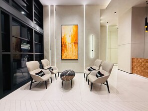 A modern lobby with a seating area, a large abstract painting, and a glass elevator. - SWNK Houze LaLaport BBCC by HomeHorizon (Kuala Lumpur)