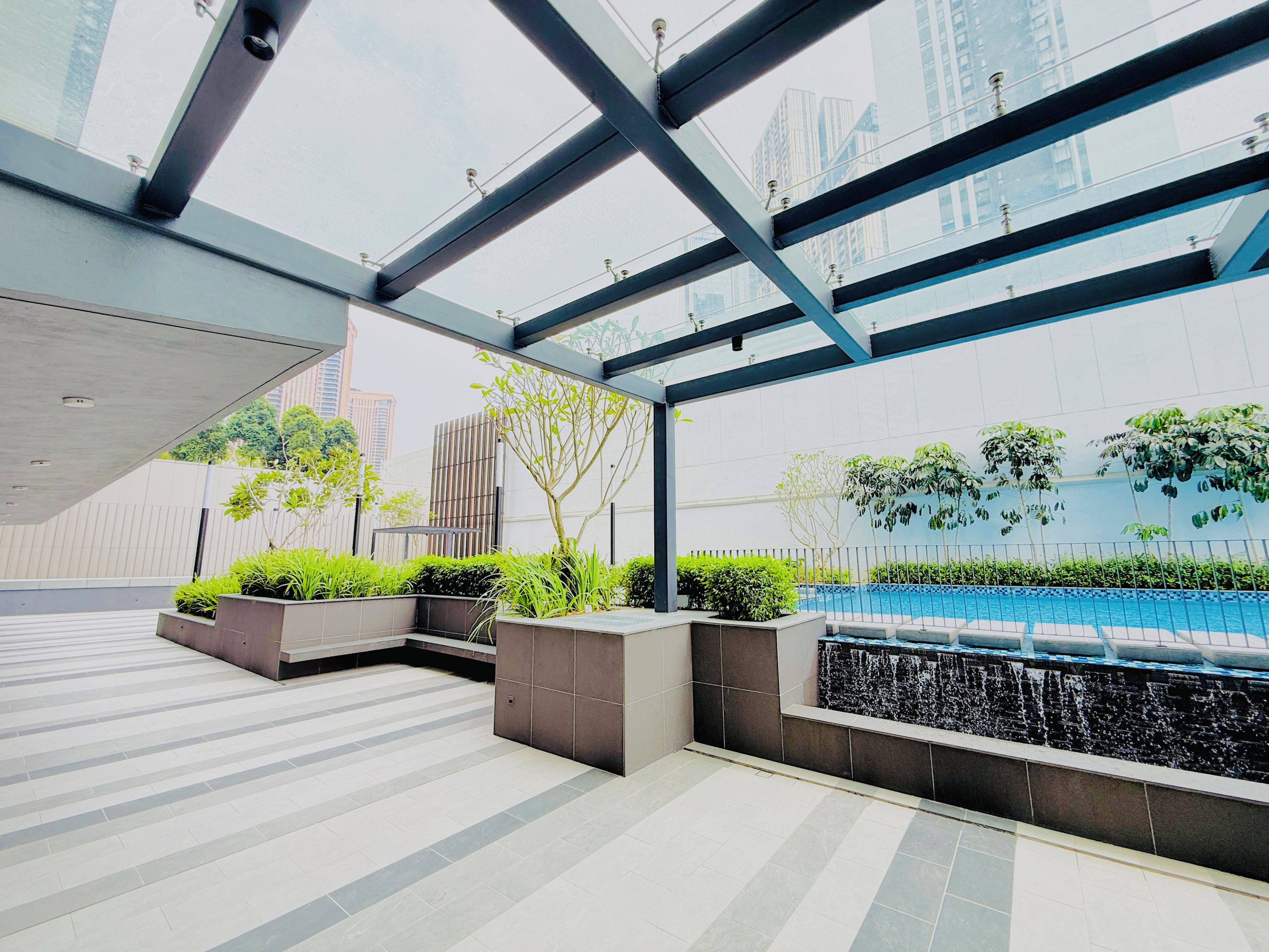 A modern outdoor area with a glass ceiling, tiled flooring, and a water feature.
