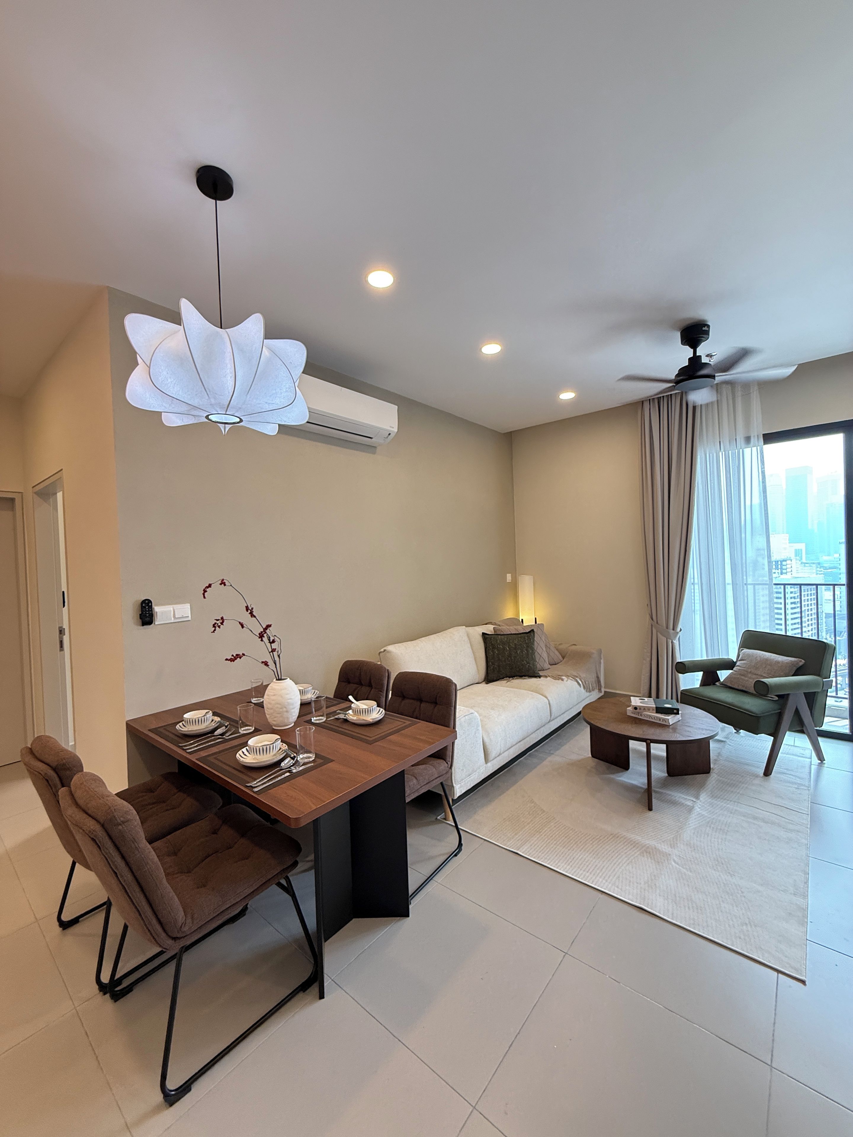 A modern living space with a dining area, sofa, and a balcony with a view.