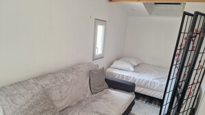 A room with a sofa, a bed, and a window. - Lovely 1-bedroom house with AC in quaint Reignac (Reignac)