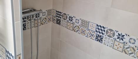 A shower area with a tiled wall, a showerhead, and a handheld shower attachment.