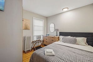 A bedroom with a bed, bedside table, lamp, and a radiator.