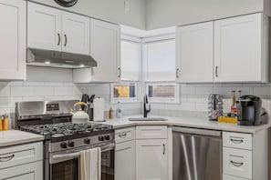 A modern kitchen with white cabinets, a stainless steel stove, and a dishwasher.