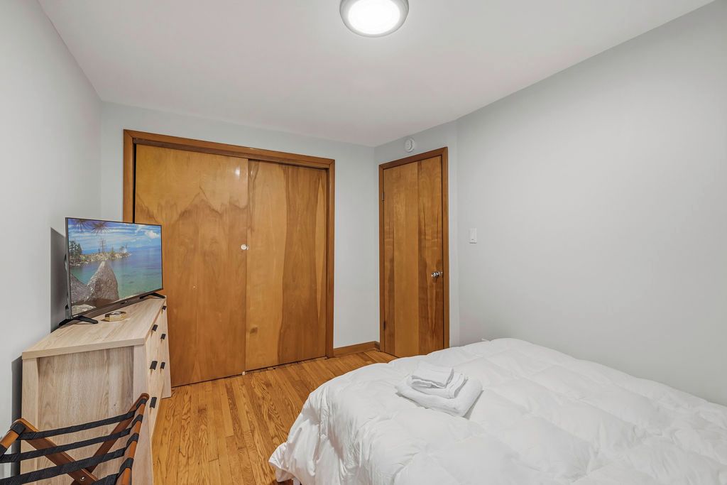 Un dormitorio con cama, un armario de madera, un escritorio con computadora y un cuadro en la pared.