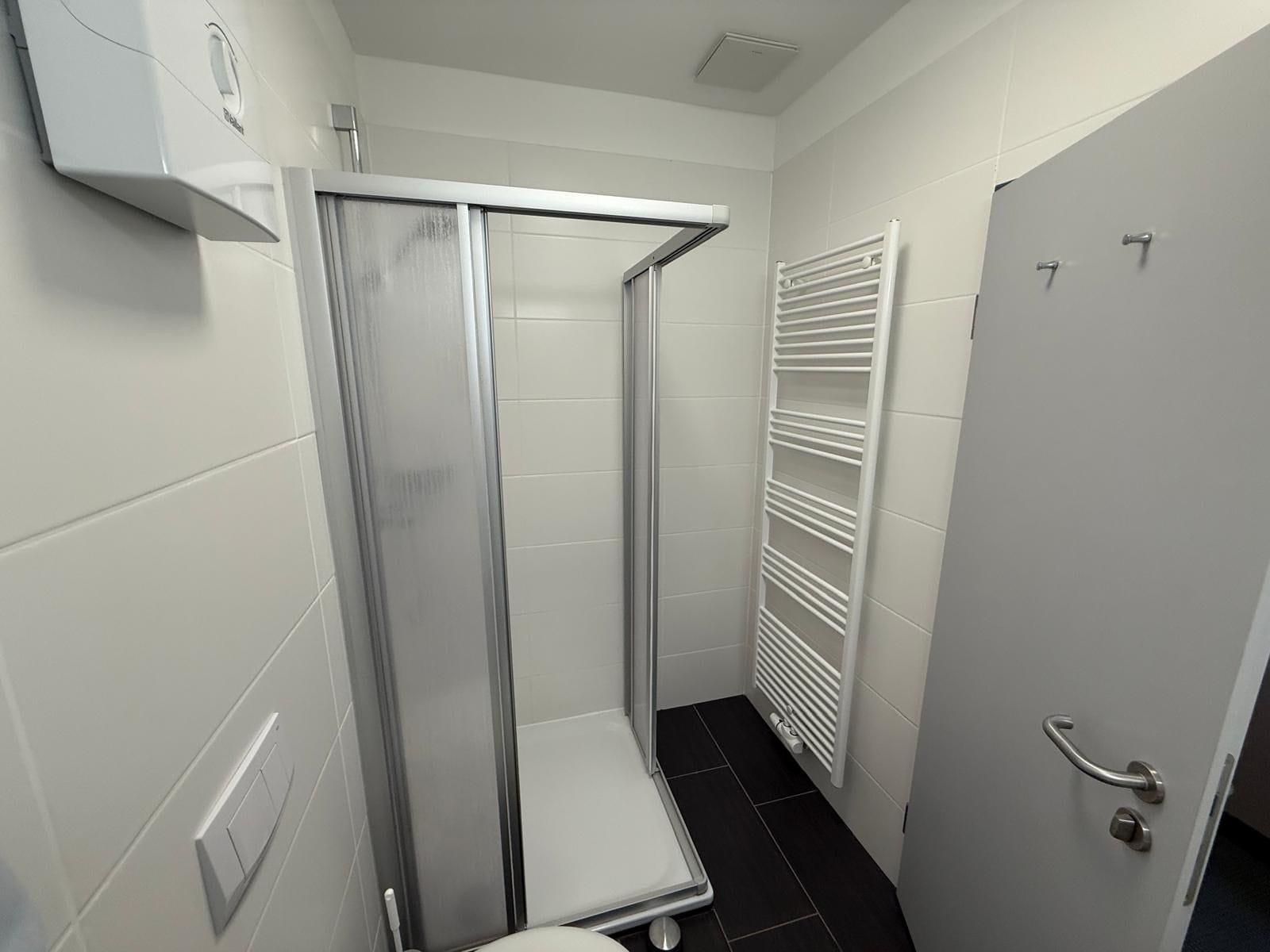 Un baño con ducha, inodoro, toallero y puerta.