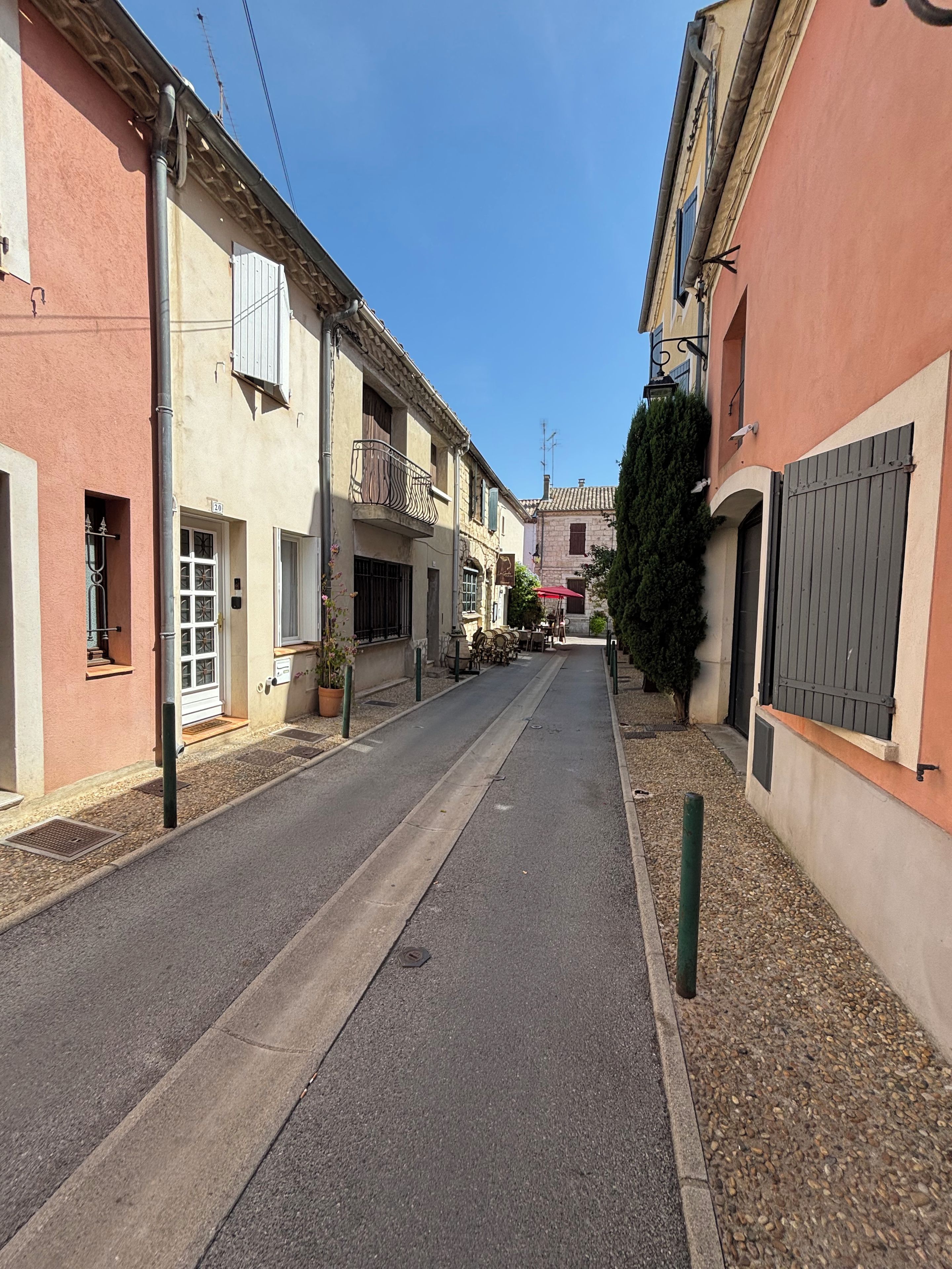 Une rue étroite bordée d’immeubles, dont certains sont dotés de balcons et de fenêtres, et un ciel bleu azur au-dessus.