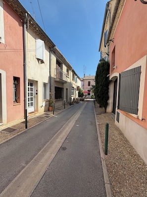 Una calle estrecha flanqueada por edificios, algunos con balcones y ventanas, bajo un cielo azul despejado.