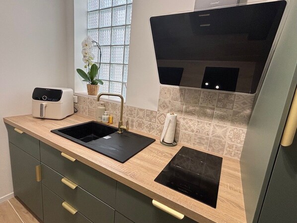 A modern kitchen with a black sink, a built-in oven, and a countertop with a toaster. - L'Intramuros ★ A/C & Free Parking Pass in the Heart of the Ramparts (Aigues-Mortes)