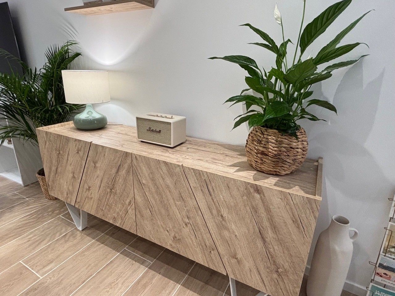 A wooden console table with a radio, a potted plant, and a woven basket.