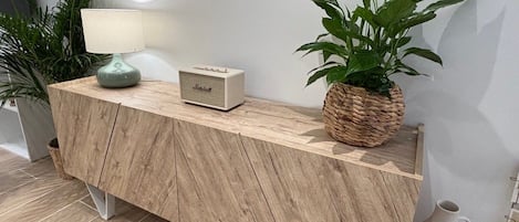 Ein Holzkonsolentisch mit einem Radio, einer Topfpflanze und einem gewebten Korb.