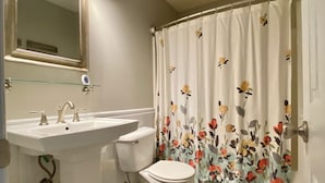 Ein Badezimmer mit weißem Waschbecken, WC und Duschvorhang mit floralem Muster.