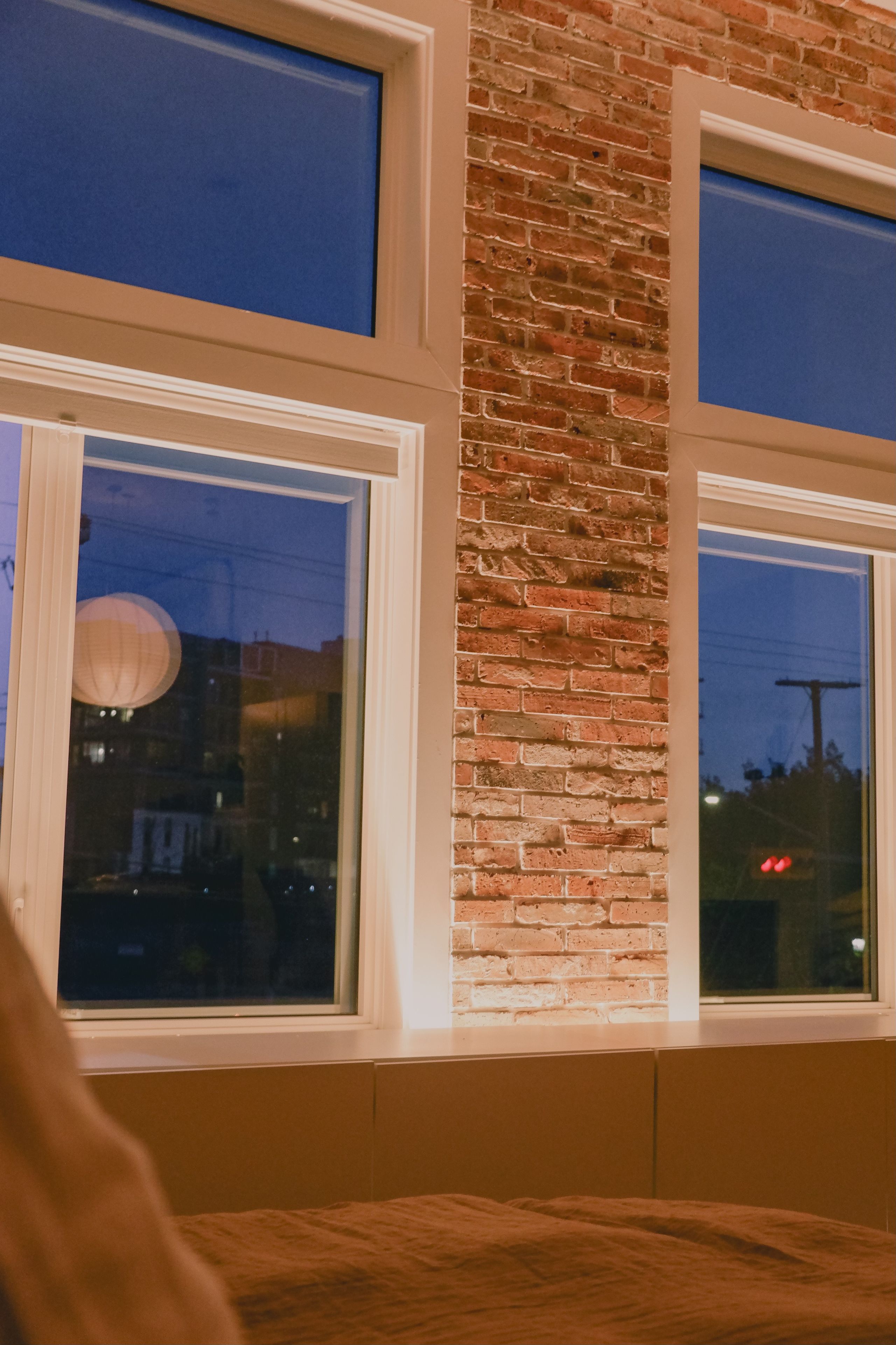 A room with a brick wall and three windows.