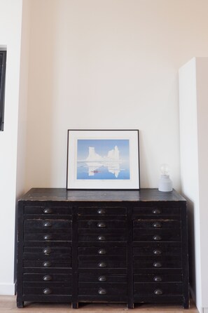 A black dresser with multiple drawers and a framed picture of a ship on the wall above it. - N60 LOFT _ Inglewood (Calgary)