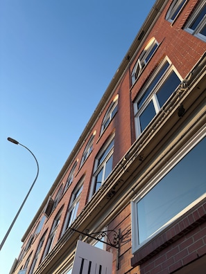 A multi-story building with a brick facade, large windows, and a street lamp. - N60 LOFT _ Inglewood (Calgary)