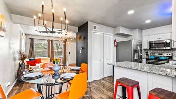 A modern kitchen with a central island, white cabinetry, and stainless steel appliances.