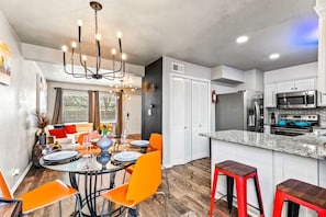 A modern kitchen with a central island, white cabinetry, and stainless steel appliances. - Stylish & Comfy Downtown Gem ~ Workspace ~ Parking (Irving)