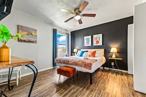 A modern bedroom with a bed, bedside tables, a ceiling fan, and a window with curtains. - Stylish & Comfy Downtown Gem ~ Workspace ~ Parking (Irving)