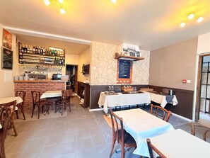 A restaurant interior with tables, chairs, a bar area, and a menu board.