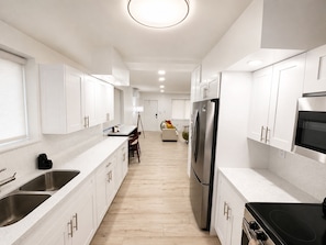 A modern kitchen with white cabinetry, stainless steel appliances, and a central island. - Cozy 1-bedroom house in enchanting Miami with AC (Miami)