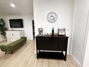 A living room with a sofa, a coffee station, and a television on the wall. - Cozy 1-bedroom house in enchanting Miami with AC (Miami)