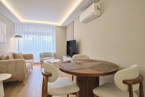 A modern living room with a round dining table, two sofas, a TV, and a large window with curtains. - Tal, 2br, Premium, Brand New (Istanbul)