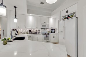 A modern kitchen with white cabinetry, a large island, and a built-in oven. - Waterfront Oasis • Pool •  Private Dock • Firepit (Marco Island)