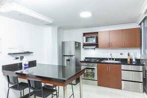 Eine kompakte Küche mit schwarzer Arbeitsplatte, Edelstahlgeräten und Holzschränken.