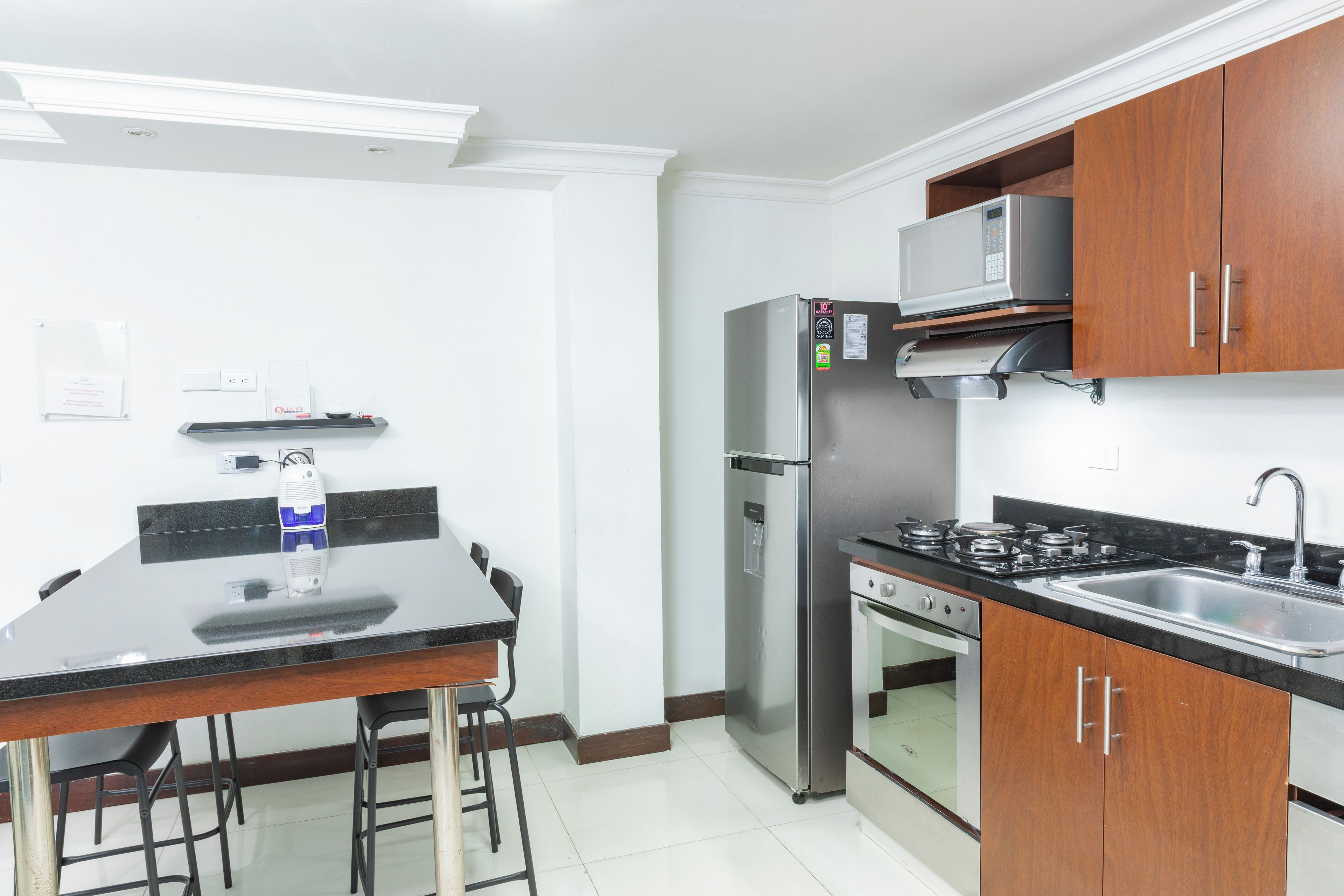 A compact kitchen with a refrigerator, microwave, stove, and sink.