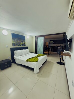 A hotel room with a bed, a nightstand, a wall-mounted TV, and a cityscape painting. - Charming 2-bedroom apartment with AC in vibrant Provenza (Medellín)