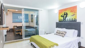 Une chambre d’hôtel avec un lit, une télévision, un tableau et une porte-fenêtre coulissante donnant sur un balcon.