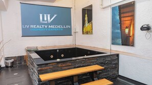 Wellnessbereich mit Whirlpool, Holzbänken und einem Schild für LIV Realty Medellin Property Experts.